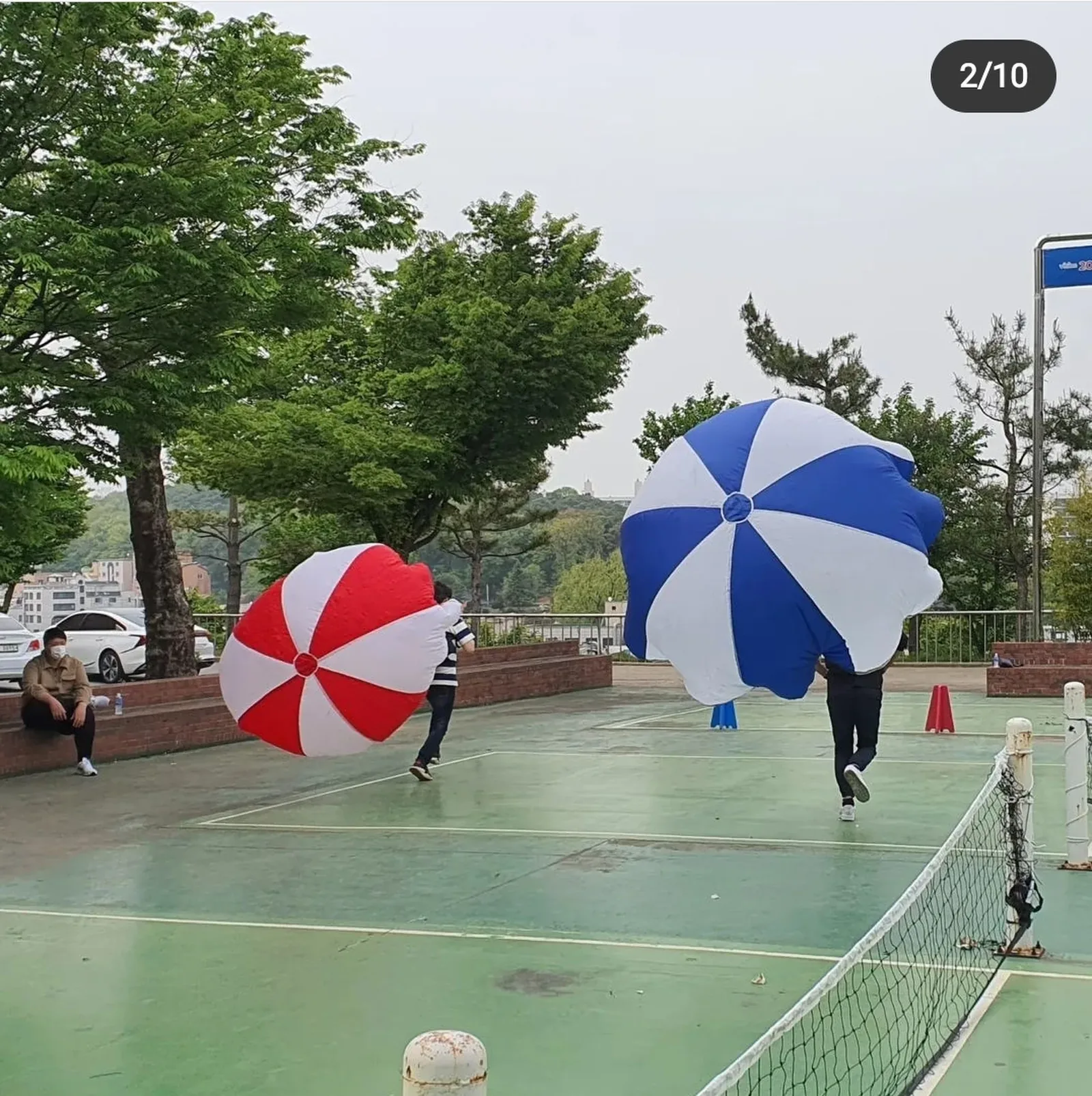 야외 코트에서 우산을 들고 진행하는 레크리에이션 게임